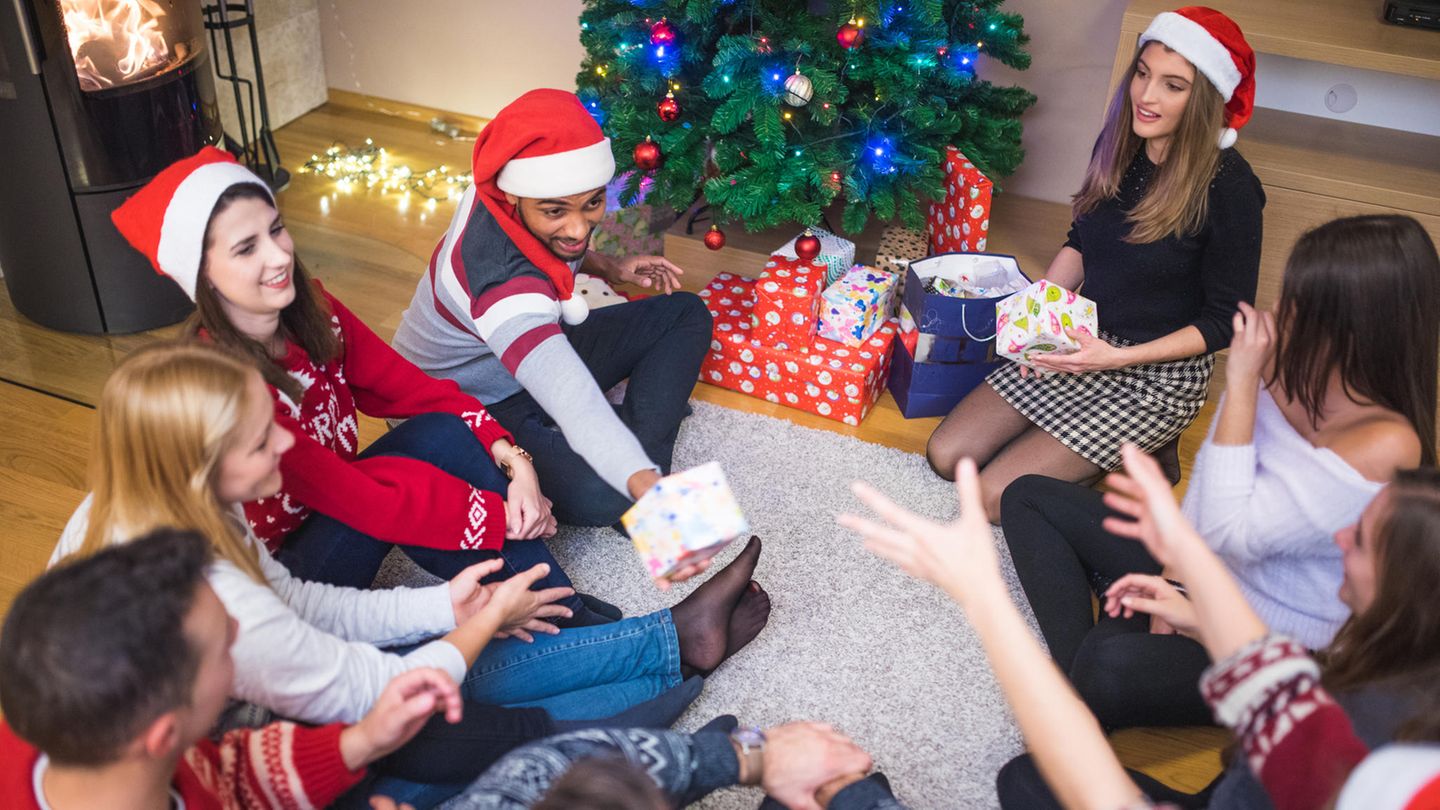 Freunde sitzen im Kreis und reichen sich Wichtelgeschenke