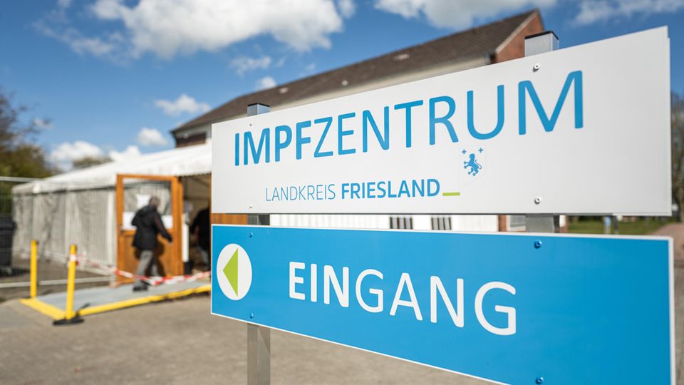 Ein weißes und ein blaues Schild weisen den Weg zum Eingang des Impfzentrums Landkreis Friesland"