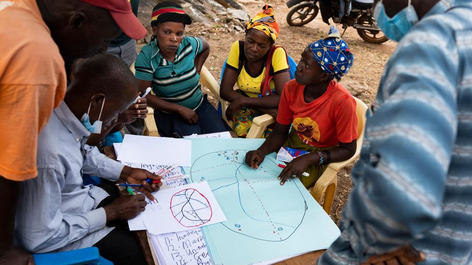 Dorfbewohner sitzen um eine Karte und planen