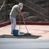 Ein Mann fegt die dicke Ascheschicht in seinem Hof zusammen.