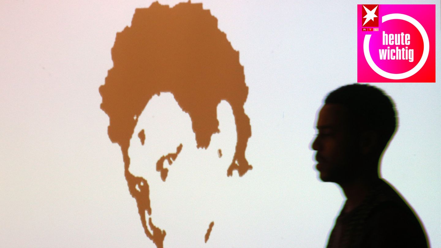 Die Konturen eines Mannes gehen auf ein an die Wand projiziertes Konterfei von Oury Jalloh zu