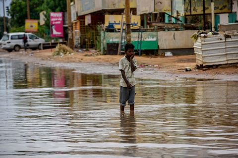 Ein Junge steht in einer überfluteten Straße im Sudan.