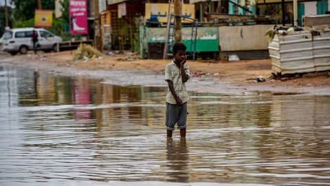 Ein Junge steht in einer überfluteten Straße im Sudan.