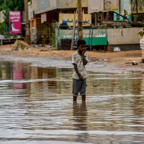 Ein Junge steht in einer überfluteten Straße im Sudan.