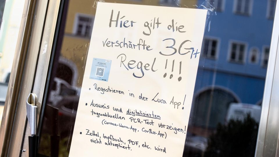 Auf einem Zettel an einer Scheibe von einem Café wird auf die Anwendung der verschärften "3G+ Regeln" hingewiesen