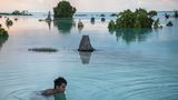 Junge schwimmt durch überflutete Teile von Kiribati