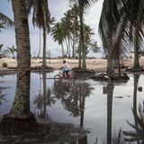 Ein Junge fährt durch überschwemmte Gebiete auf Tuvalu