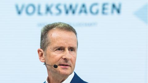 VW-Chef Herbert Diess spricht in ein Mikro, darüber der Schriftzug "Volkswagen"