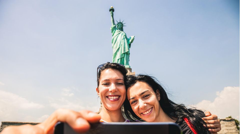 Zwei junge Frauen mache ein Selfie vor der Freiheitsstatue in den USA