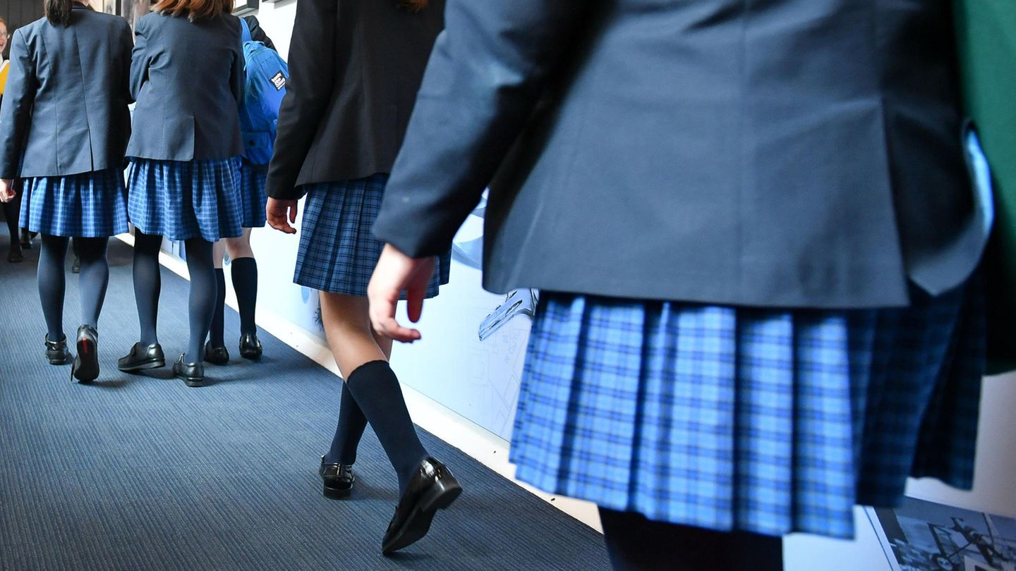 Schüler in Schuluniform gehen einen Gang entlang.