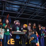 Vertreter indigener Völker stehen auf der Bühne am George Square