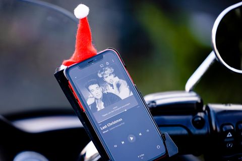 Auf dem Display eines Smartphones in einer Auto-Halterung leuchtet das Cover von "Last Christmas" von Wham!