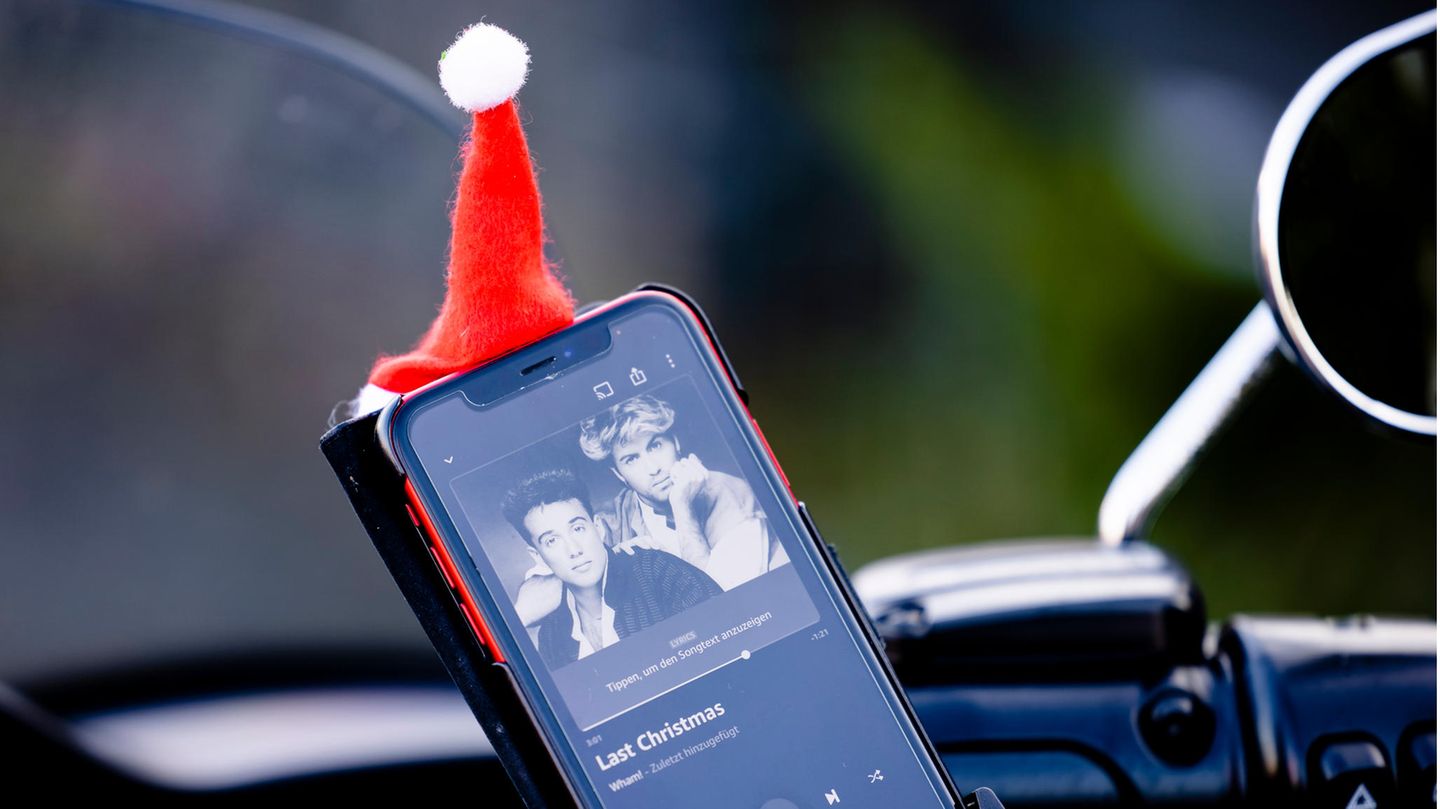 Auf dem Display eines Smartphones in einer Auto-Halterung leuchtet das Cover von "Last Christmas" von Wham!