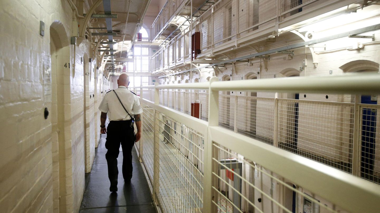 Ein Gefängniswärter läuft an Gefängniszellen vorbei