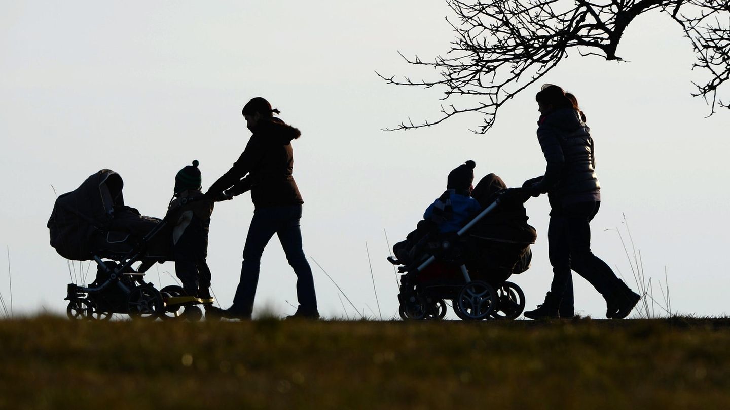Zwei Frauen schieben ihre Kinderwagen eine Landstraße entlang