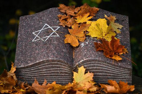 Herbstlaub liegt auf einem Gedenkstein mit dem Davidstern während einer Gedenkstunde auf dem jüdischen Friedhof