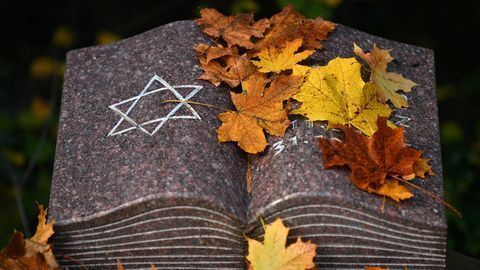 Herbstlaub liegt auf einem Gedenkstein mit dem Davidstern während einer Gedenkstunde auf dem jüdischen Friedhof