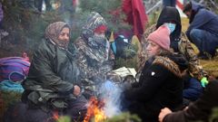 Vier Frauen sitzen in Mützen und Kopftüchern sowie warmer Kleidung um ein Lagerfeuer herum