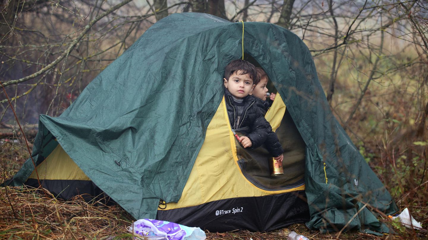 Zwei kleine Jungs schauen aus dem halb geöffneten Eingang eines grün-gelben Iglu-Zeltes