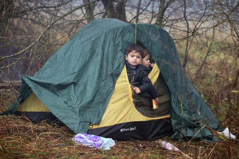 Zwei kleine Jungs schauen aus dem halb geöffneten Eingang eines grün-gelben Iglu-Zeltes