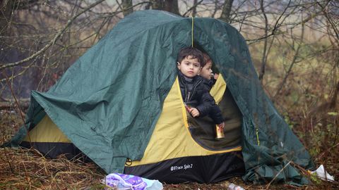 Zwei kleine Jungs schauen aus dem halb geöffneten Eingang eines grün-gelben Iglu-Zeltes