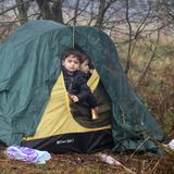 Zwei kleine Jungs schauen aus dem halb geöffneten Eingang eines grün-gelben Iglu-Zeltes