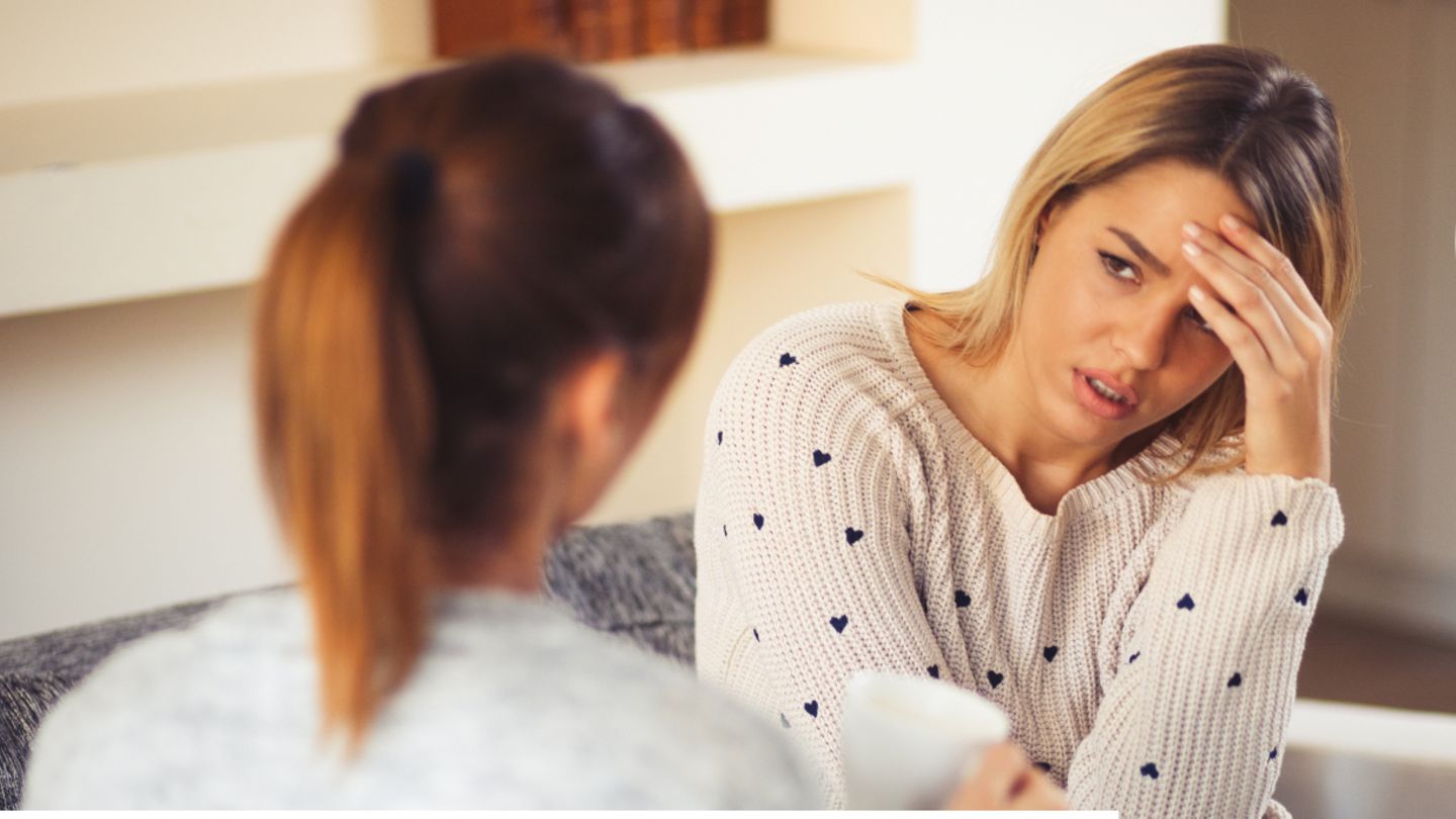 Zwei Freundinnen sitzen auf der Couch und sprechen über ihre Freundschaft