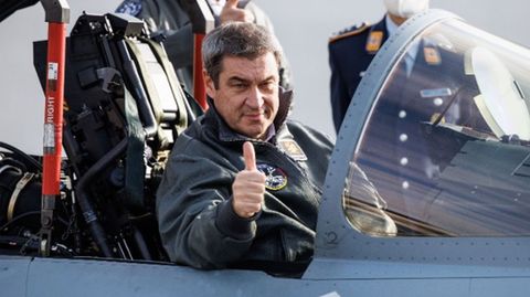 Markus Söder macht eine "Daumen-Hoch"-Geste aus dem Cockpit eines Eurofighter-Jets hinaus.
