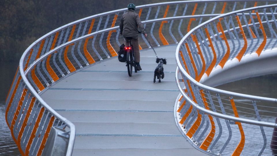 Ein Mann radelt mit seinem Hund über die im September 2021 eröffnete neue Fahrradbrücke in Mecklenburg-Vorpommern.
