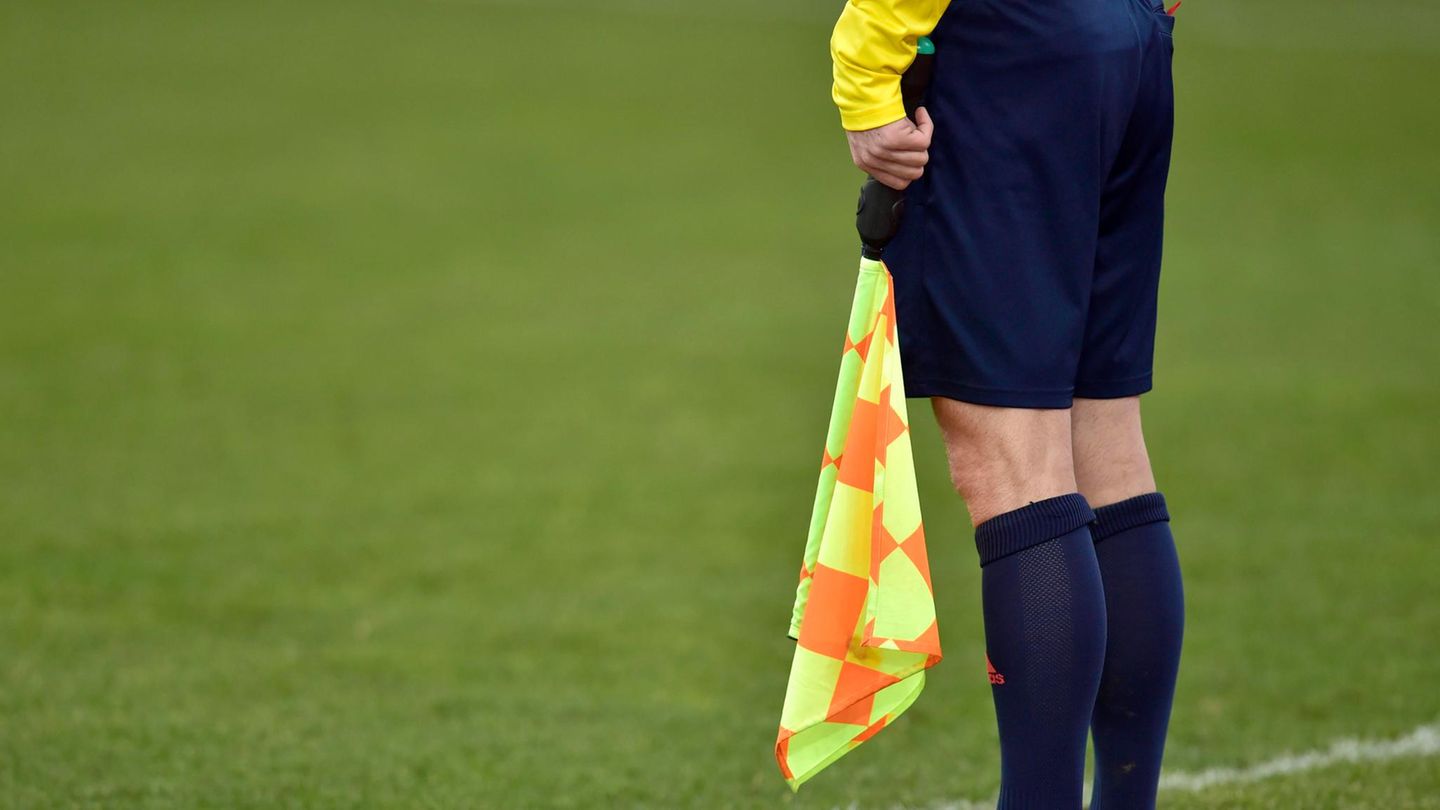 Linienrichter steht an der Seitenlinie eines Fußballfeldes.