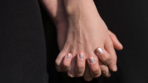 Zwei lesbische Frauen fassen sich an den Händen (gestellte Szene).