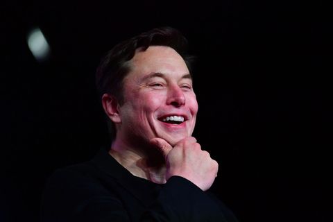 Elon Musk fässt sich lachend ans Kinn.