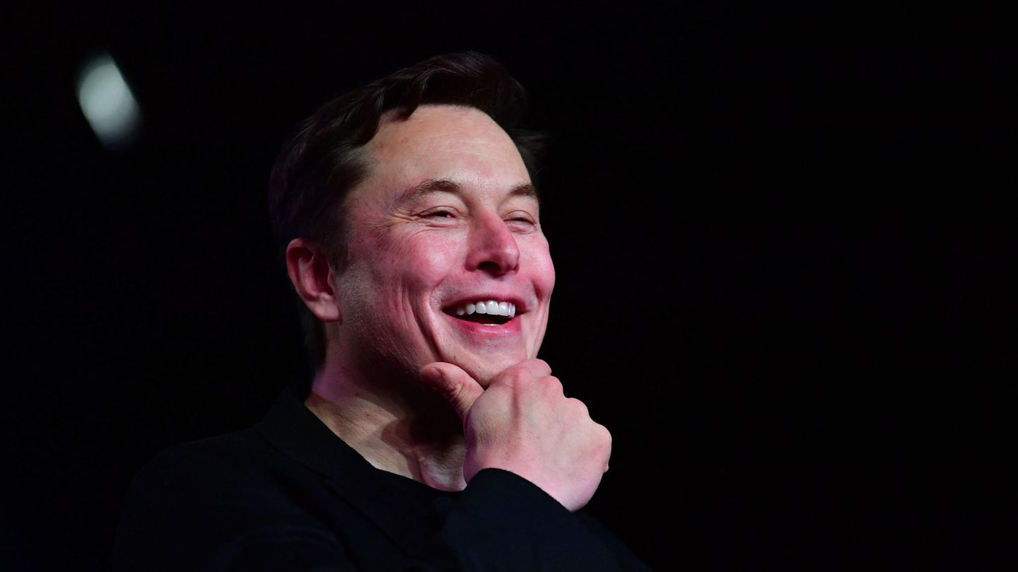 Elon Musk fässt sich lachend ans Kinn.