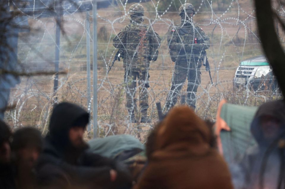 Polnisches Militär behält die Geflüchteten hinter dem Stacheldrahtzaun auf belarussischer Seite der Grenze im Auge.