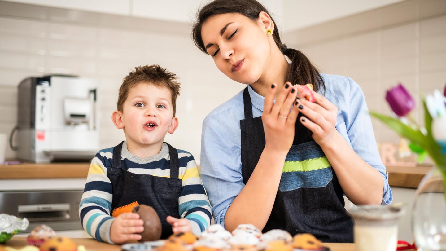 Eine Mutter und ihr Sohn probieren selbstgebackene Schokoladenkekse