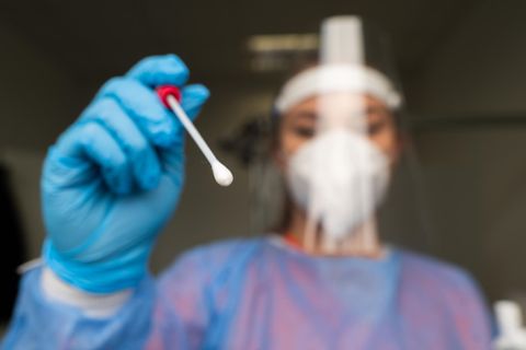 Eine Mitarbeiterin einer Coronavirus-Teststation hält ein Teststäbchen bereit