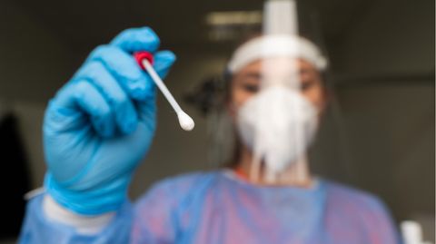 Eine Mitarbeiterin einer Coronavirus-Teststation hält ein Teststäbchen bereit