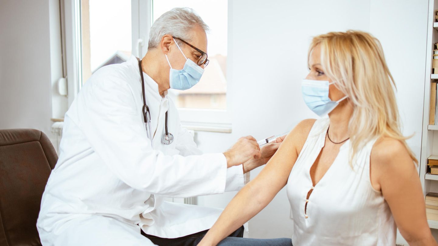 Ein Arzt impft eine Patientin