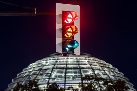 Eine Ampel vor der Kuppel des Reichstagsgebäudes leuchtet in einer Langzeitbelichtung in allen drei Phasen