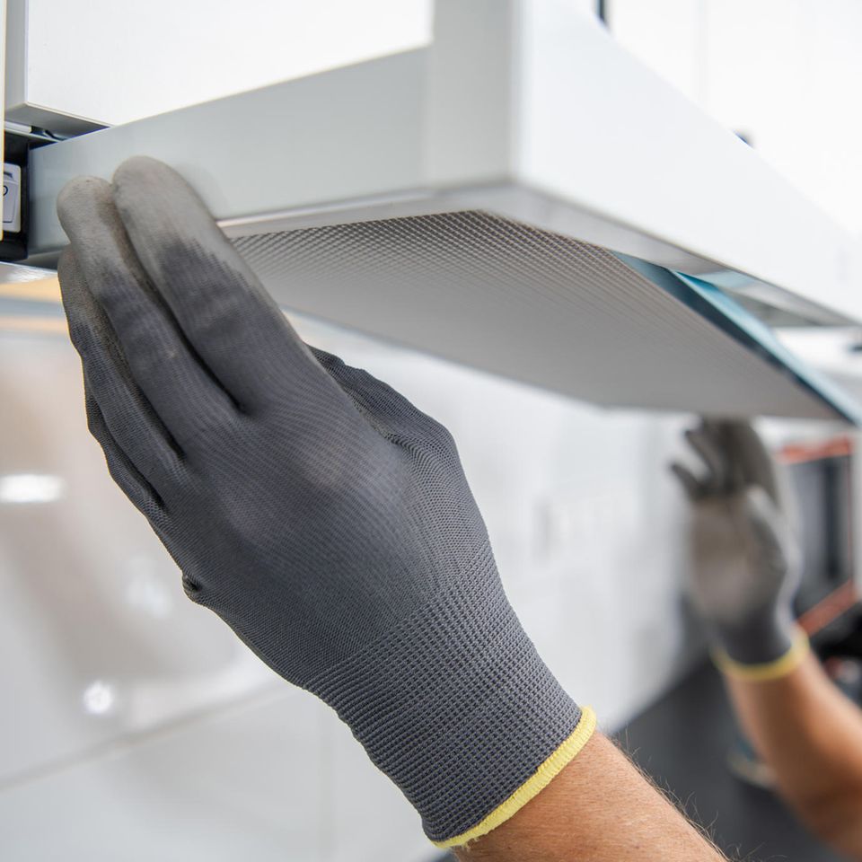 Ein Mann entfernt den Filter einer Dunstabzugshaube