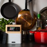 Sonoro Stream: In der Küche spiel die Musik!  Spätestens seit den Corona-Lockdowns ist die Küche wieder zum zentralen Ort des Haues geworden. Viele kochen und backen seither häufiger selbst. Was in jeder Küche nicht fehlen sollte, ist die passende musikalische Untermalung oder der Lieblingspodcast. Das kann man zwar auch mit dem Smartphone machen, doch mit fettigen oder nassen Händen wird das schnell unpraktisch.  Der nordrhein-westfälische Audiospezialist Sonoro hat für fettig-feuchte Umgebungen den Sonor Stream entwickelt. Das moderne "Kofferradio" klingt nicht nur gut, sondern kann nahezu jede Audioquelle anzapfen: von USB, Bluetooth, DAB+ bis hin zu tausenden Internet-Radiosendern oder direkt von Spotify über WLAN. Ganz die alte Schule ist es hingegen bei der Bedienung: Eine schöne alte wasserfeste Fernbedienung und einen einzigen Drehknopf statt Smartphone-App. 