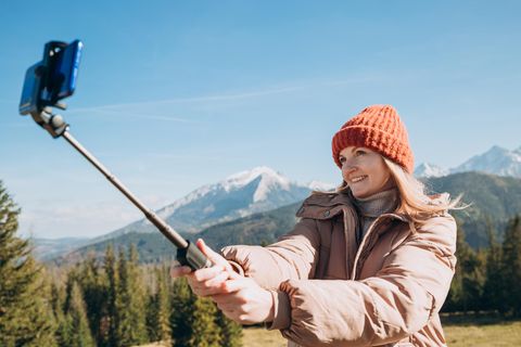 Eine Frau hält einen Selfiestick in der Hand