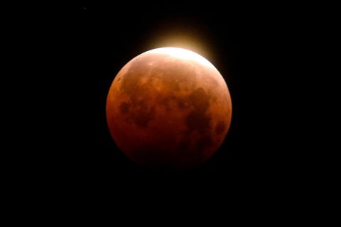 Ein rötlicher Mond vor einem schwarzen Himmel