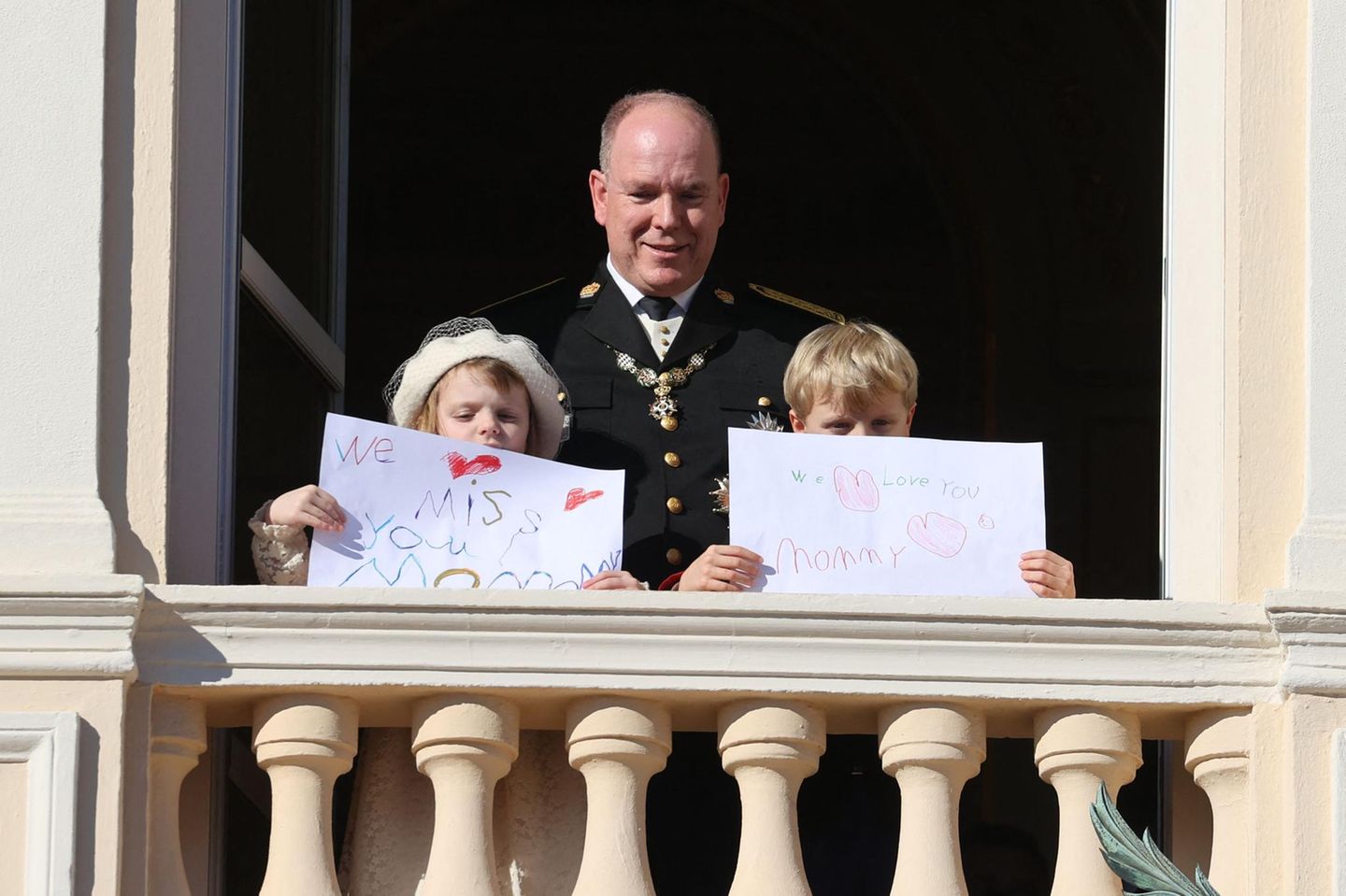Es war der emotionale Höhepunkt dieses Nationalfeiertags: Erbprinz Jacques und Prinzessin Gabriella zeigten auf dem Balkon des Schlosshofes selbstgeschriebene Schilder, in denen sie an ihrer abwesende Mutter erinnerten. Aufgrund einer schweren Erkrankung konnte Charlène der Zeremonie nicht beiwohnen. Ihre Kinder lassen sie auf diesem Wege wissen, dass sie sie lieben und vermissen. 