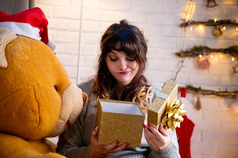 Frau öffnet Geschenk und ist unzufrieden