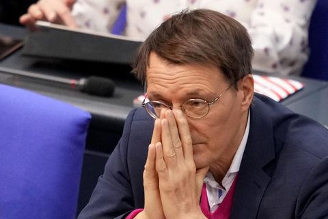 Ein weißer Mann mit rundlicher Metallbrille und braunem Seitenscheitel legt im Bundestag seine Hände vor dem Mund aneinander