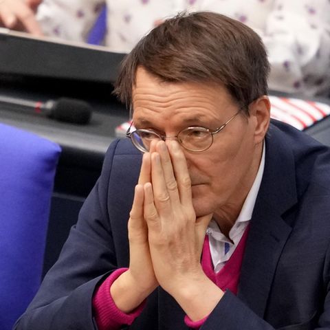Ein weißer Mann mit rundlicher Metallbrille und braunem Seitenscheitel legt im Bundestag seine Hände vor dem Mund aneinander