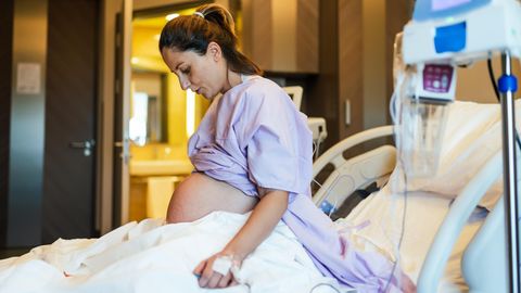 Hochschwangere sitzt im Krankenhausbett