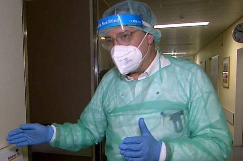 Ein Arzt in Schutzkleidung steht in einem Krankenhausflur.