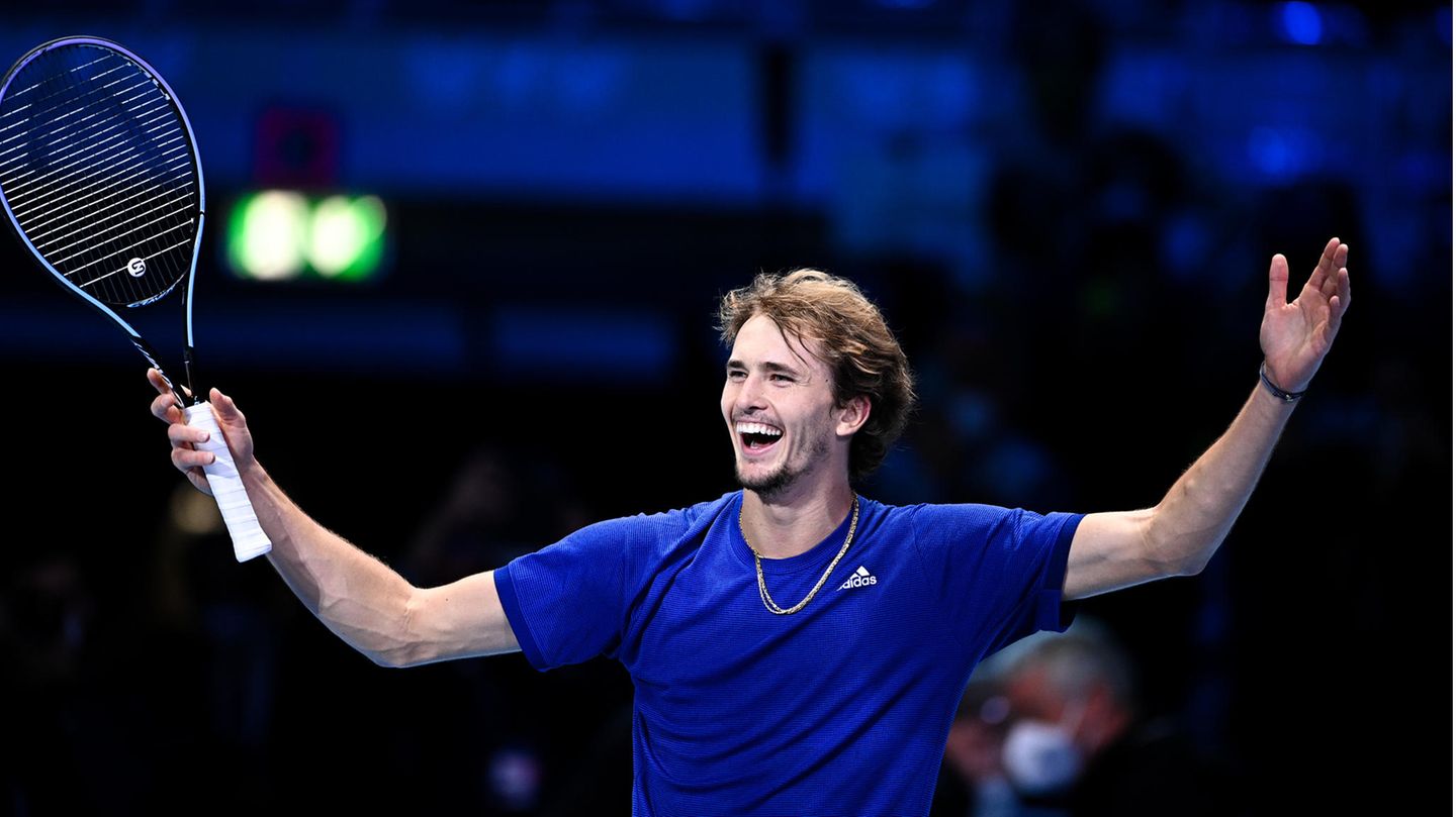 Lachender Alexander Zverev mit erhobenen Händen und Tennisschläger Lachender Alexander Zverev mit erhobenen Händen und Tennisschläger